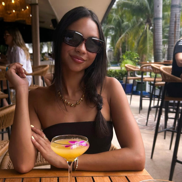 Woman holding a cocktail in an outdoor cafe setting