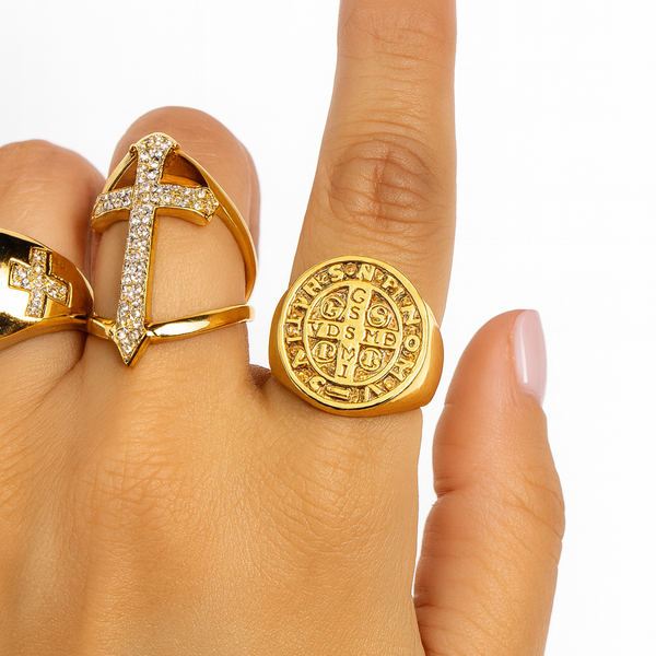 Gold ring with intricate design on a hand against a white background