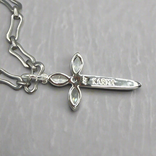 Silver bracelet with a cross-shaped charm labeled 'Karma' on a light gray background