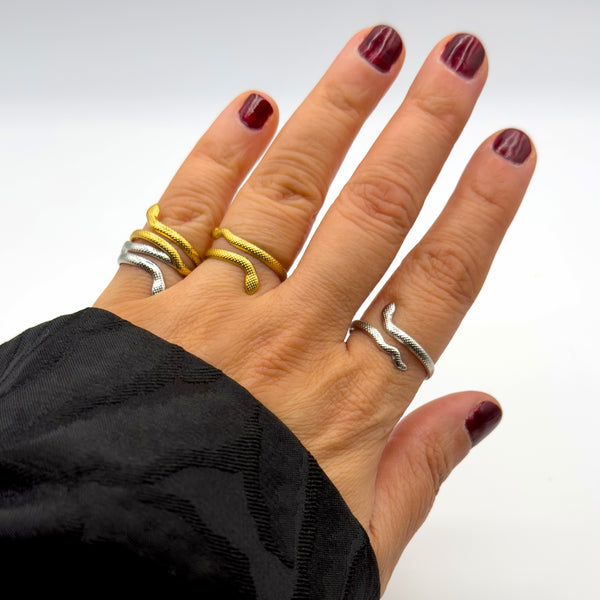 Hand wearing multiple rings on a plain background