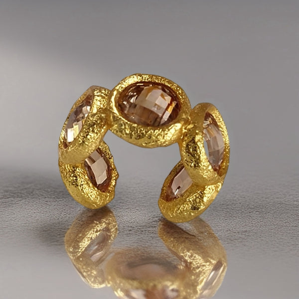 Gold ring with embedded stones on a reflective surface