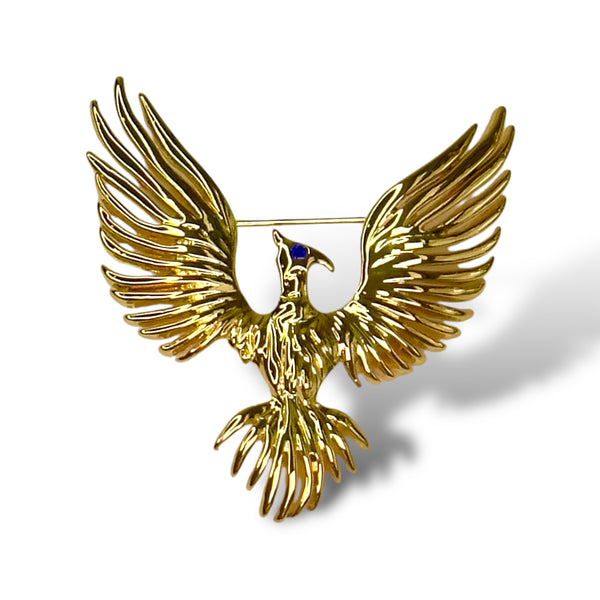 Phoenix Brooch in yellow gold with Saphire blue eyes agains white background Jagged halo Jewelry