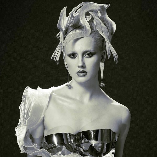 Black and white portrait of a person with elaborate hair and a detailed garment against a dark background