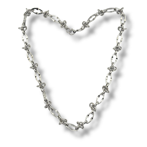 Silver chain necklace forming a heart shape on a white background