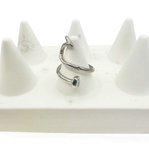 Silver ring with a central gemstone on a white stand