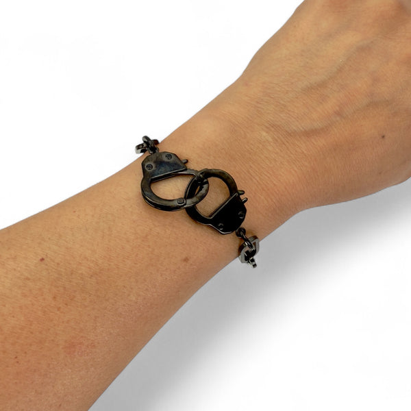 Bracelet shaped like handcuffs on a wrist against a white background