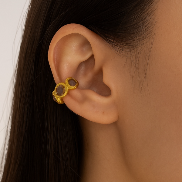 Gold earring worn by a person with dark hair.