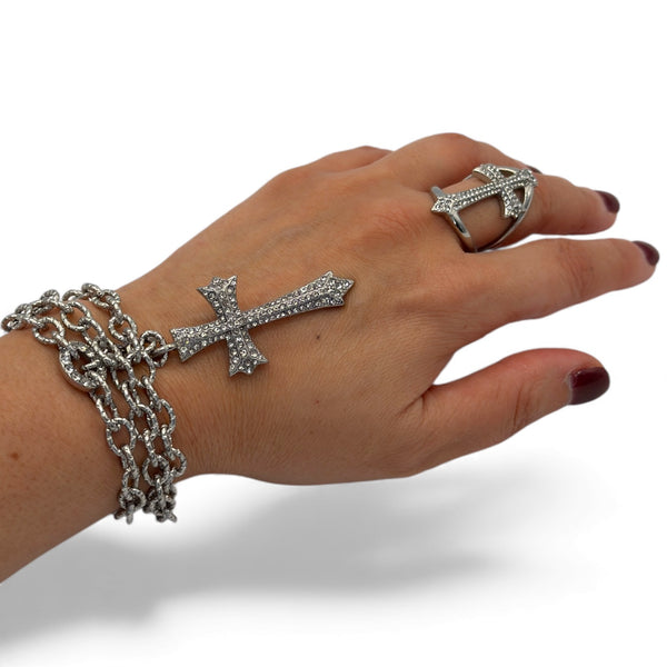 Hand wearing a silver bracelet and ring on a white background saints cross necklace and ring by jagged halo jewelry