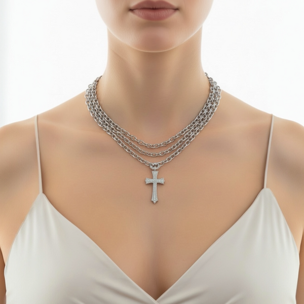 Woman wearing a silver chain necklace with a cross pendant on a white background