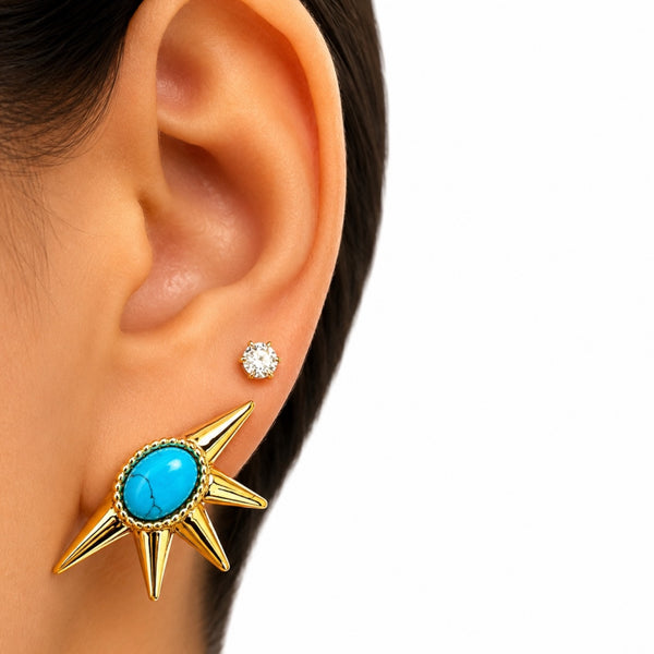Gold star-shaped earring with turquoise stone worn by a person
