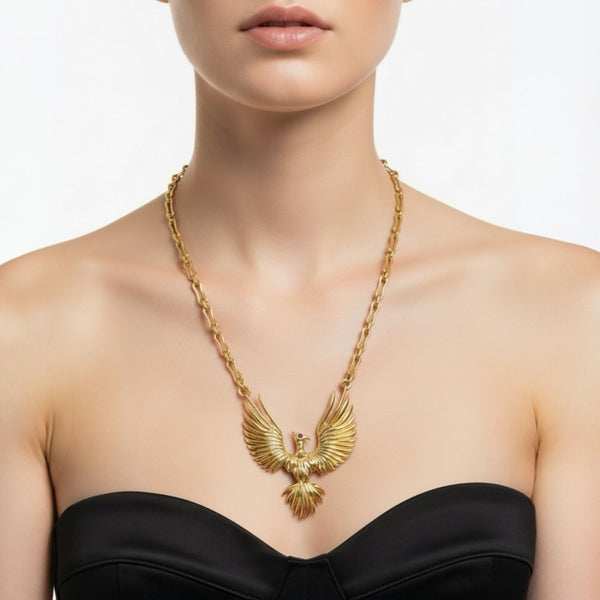 Gold phoenix pendant necklace with an blue sapphire eyes pendant worn by a model on a white background by jagged halo jewelry