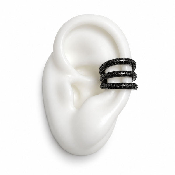 A three-band ear cuff ring with black pavé-set stones, displayed on a white silicone ear model against a clean white background.