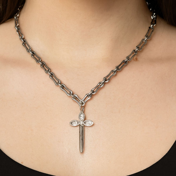 Necklace with a sword-shaped pendant on a person wearing a black top.