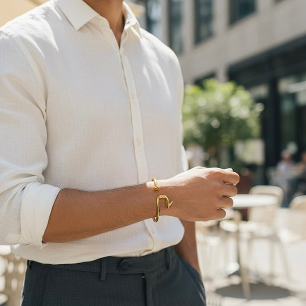 Person wearing a white shirt and gold bracelet with a blurred outdoor background
