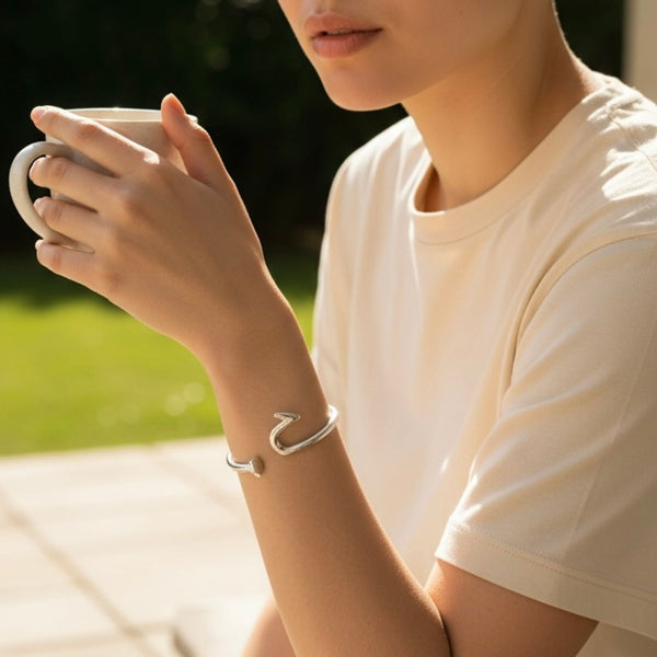 Person holding a cup outdoors with a blurred natural background
