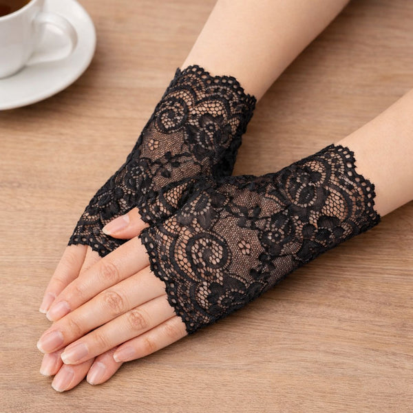 Black lace fingerless gloves on a person's hand with a cup of coffee in the background by jagged Halo jewelry