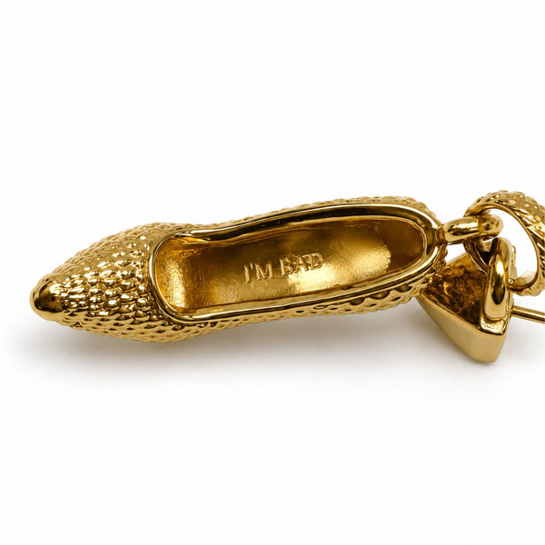 Close-up of the gold I’M BAD stiletto charm showing the engraving inside the sole
