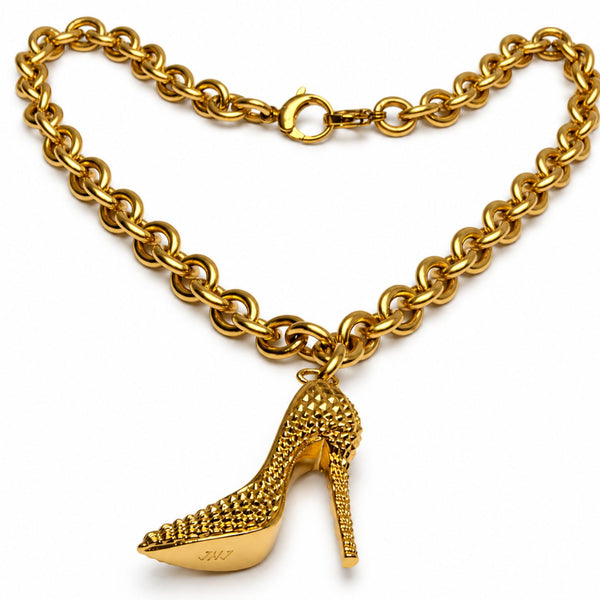A gold-tone chain necklace featuring a dangling high-heeled shoe charm, photographed on a clean white background.