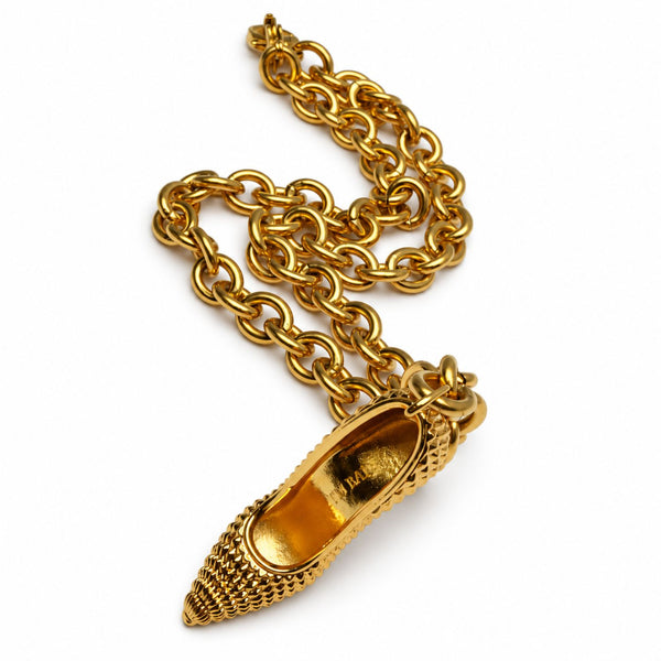A gold-tone pendant necklace featuring a detailed high-heeled shoe charm with a textured toe, suspended from a thick link chain on a white background.