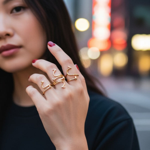 Woman wearing gold nail rings on a blurred city street background