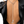 A silver chain lariat necklace with a rhinestone-embellished high-heeled shoe pendant, shown worn on a model's back over a black satin jacket.