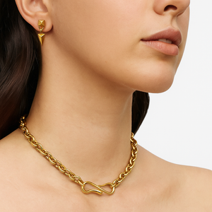 Close-up of a person wearing a gold chain necklace and matching earrings on a white background
