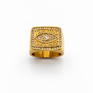 Gold ring with eye design and engraved text on a white background