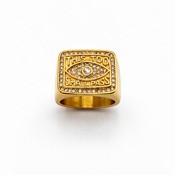 Gold ring with eye design and engraved text on a white background
