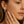 Close-up of a woman wearing diamond earrings and a ring, with a soft focus on the face.