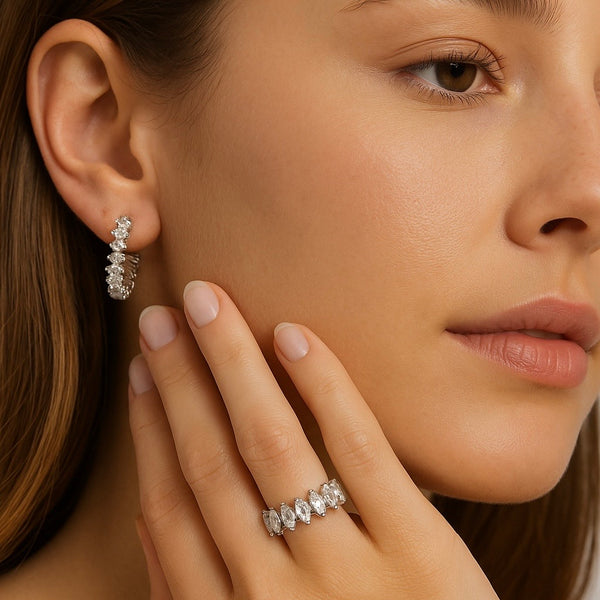 Close-up of a woman wearing diamond earrings and a ring, with a soft focus on the face.