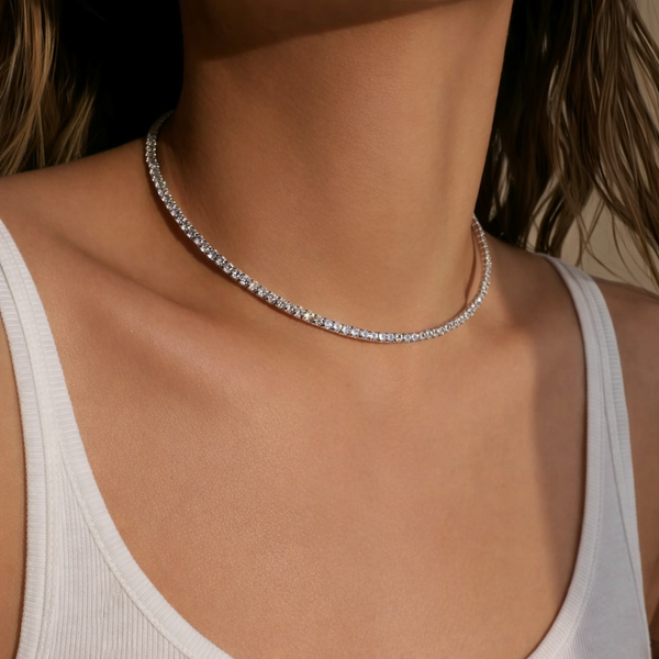 Close-up of a person wearing a silver necklace with a neutral background