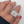 Silver ring with decorative design on a hand with red nail polish against a white background