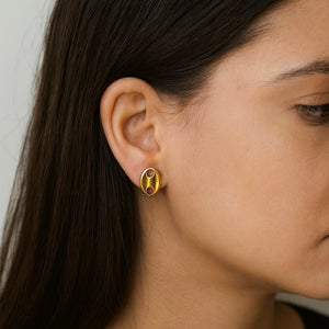 Close-up of a person wearing a gold earring with a black center.