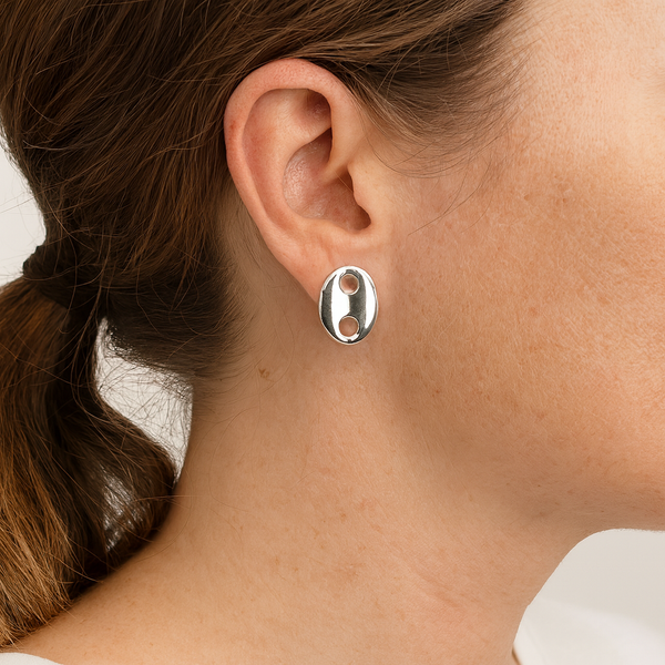 Silver earring worn by a person with a neutral background