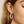 Close-up of a woman wearing diamond hoop earrings with a neutral background
