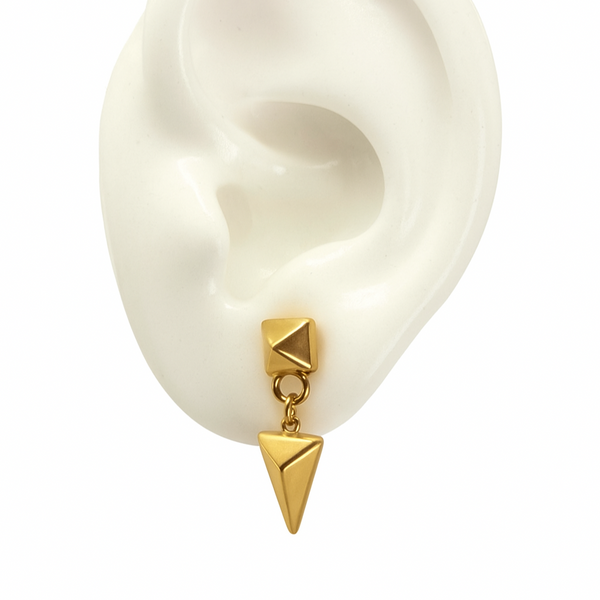 arrowhead drop earrings in yellow gold on a white silicone ear on a white background