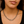 Close-up of a person wearing a silver chain necklace with a blurred background