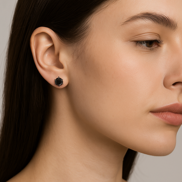 Close-up of a woman wearing black stud earrings against a neutral background
