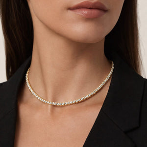 Close-up of a person wearing a delicate gold necklace against a neutral background