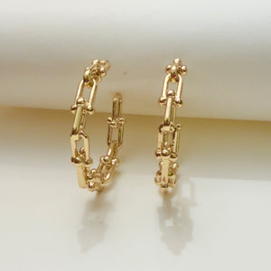 Gold chain-style earrings on a light background