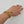 Gold bracelet with a leaf design on a wrist against a white background