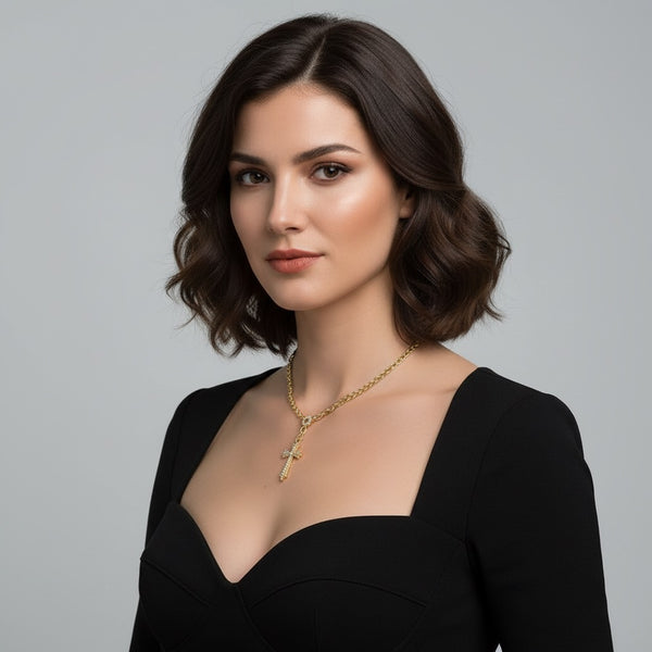 Woman wearing a black dress and gold necklace against a gray background