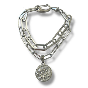 Silver chain bracelet with a round pendant on a white background
