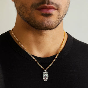 Man wearing a gold chain necklace with a pendant on a neutral background