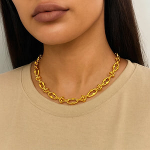 Gold chain necklace worn by a person with a neutral background