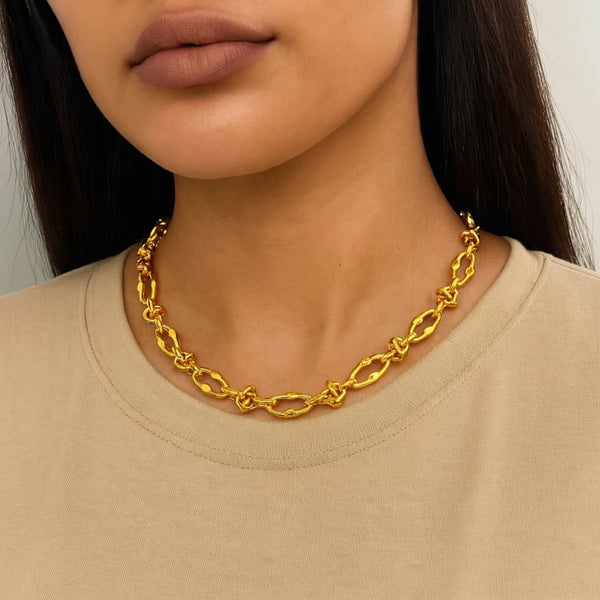 Gold chain necklace worn by a person with a neutral background