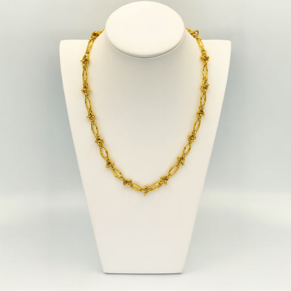 Gold chain necklace on a white mannequin bust against a light gray background