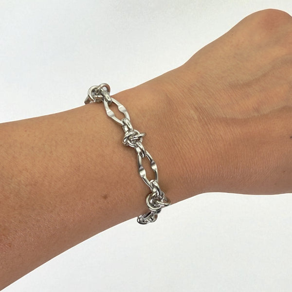 Silver chain bracelet on a wrist against a white background