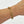 Gold chain bracelet on a wrist against a white background