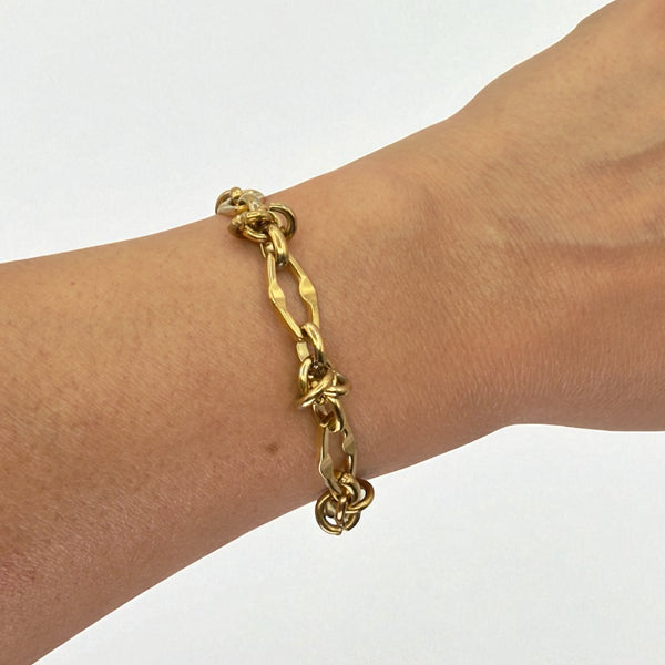 Gold chain bracelet on a wrist against a white background